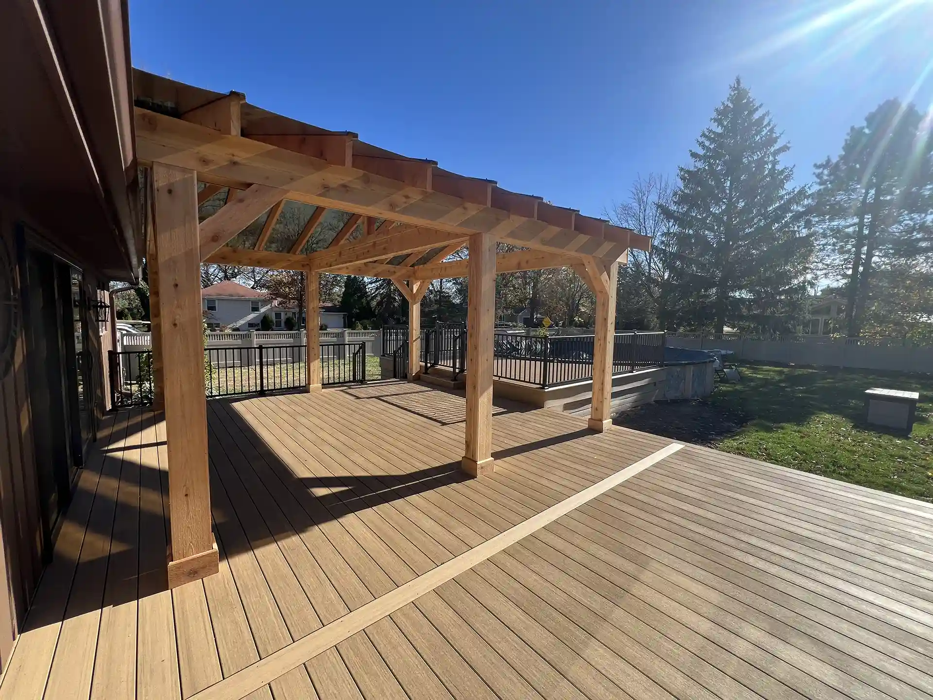 photo of a multi-level deck that includes a pool deck and pavilion with polycarbonate roof and wood beams and posts 