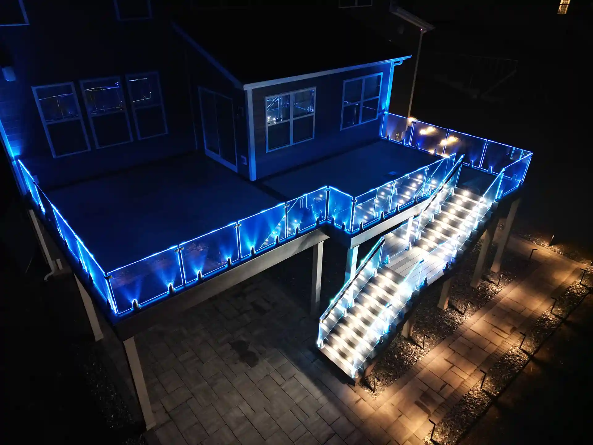 photo of an elevated deck at night that features glass panels with lighting 