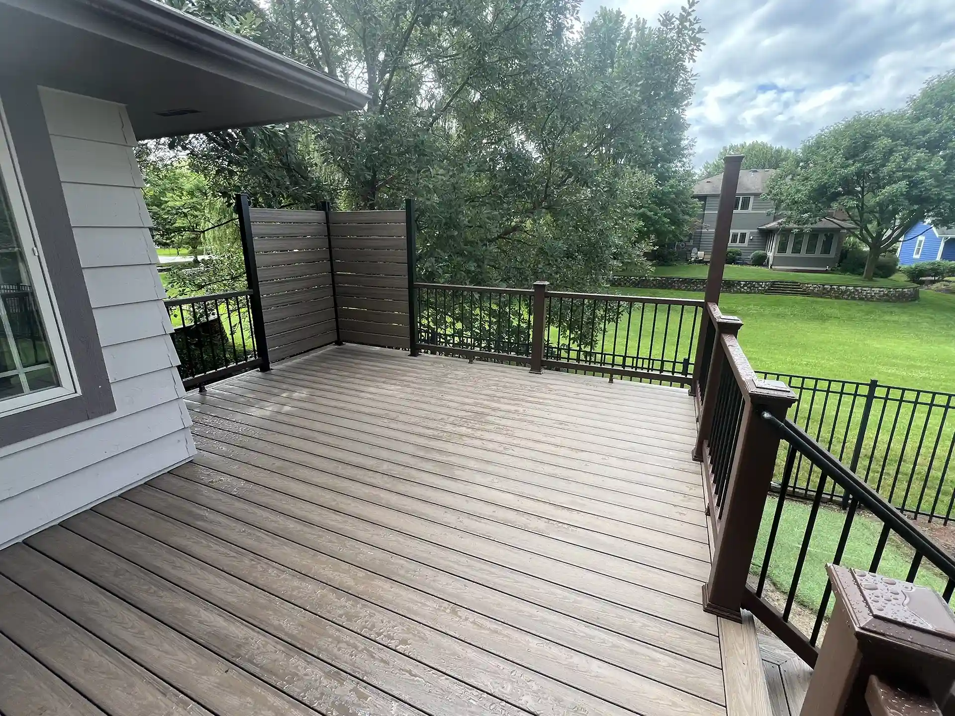 photo of a composite deck with privacy screens, deck railing, and deck steps 