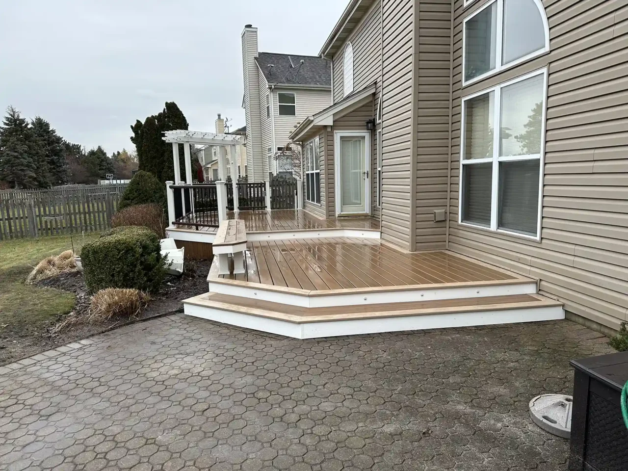 PHoto of Freshly resurfaced Trex Lineage deck in Algonquin with white-trimmed edges, built-in bench, and custom pergola over a grilling area.