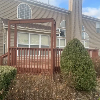 Rear view of old red wood deck in Algonquin showing faded boards, railing, and framing over the grill area before renovation.