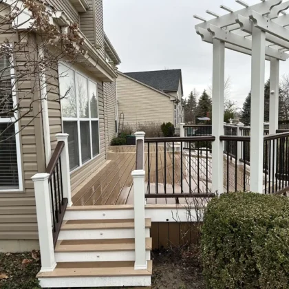 Photo of completed Trex deck in Algonquin featuring white pergola over grill area, black and white railing, and freshly resurfaced stairs.
