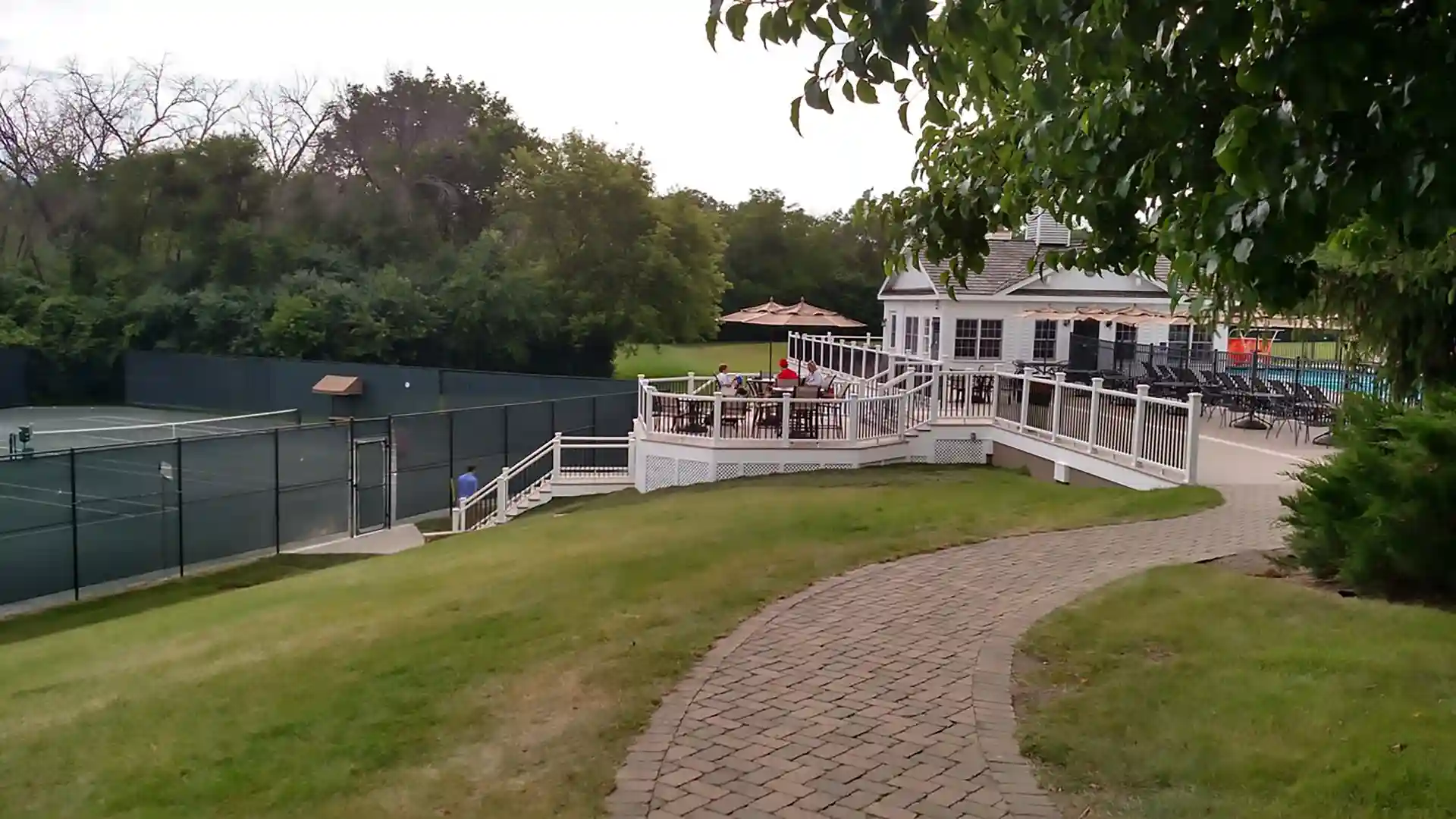 Photo of a commercial deck at a country club with is positioned between the clubhouse and pool area and the tennis courts.
