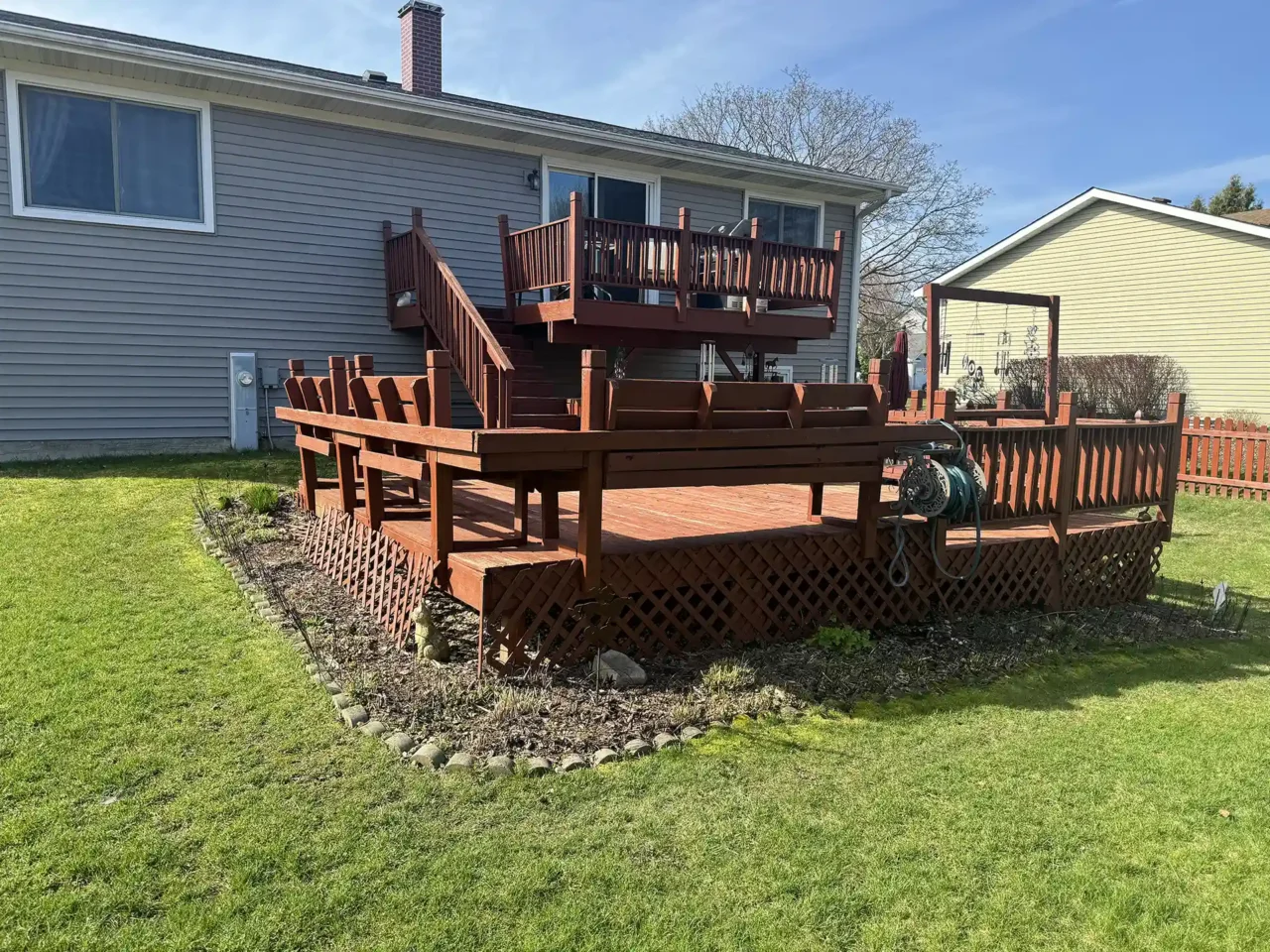 Photo of the original red wood deck with patio furniture and lattice skirting, showing weathering and age.