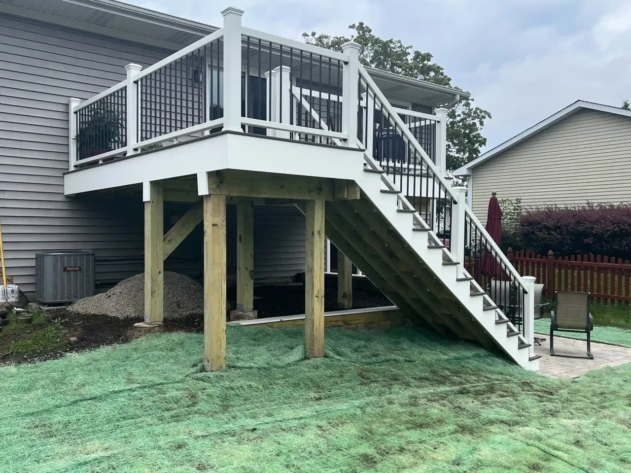 Photo of the new composite deck with white railings and black balusters, featuring an updated staircase and clean framing.