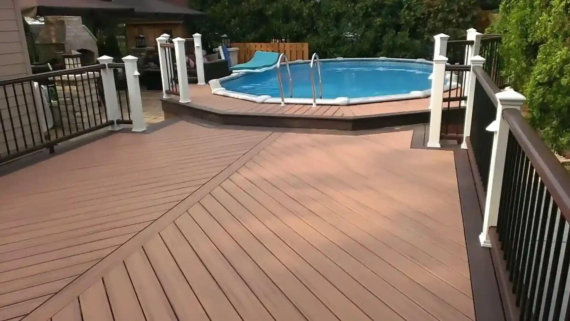 Photo of spacious composite deck with railing, leading to round above-ground pool.